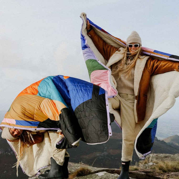 VOITED Cloudtouch Value Set bundle offer: two women on a mountaintop holding two Cloudtouch blankets with a colorful patchwork design and sherpa lining, fluttering in the wind.